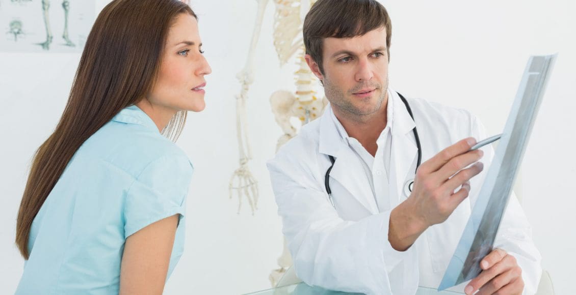 chiropractor discusses x-ray with patient