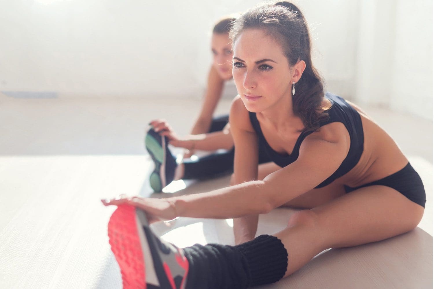 women stretch out legs before workout