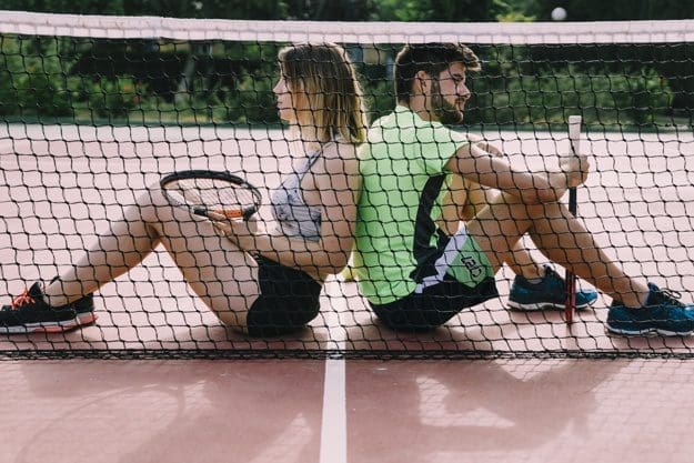 tennis elbow players taking break sitting by the net